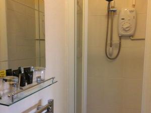 a bathroom with a shower with a mirror and a sink at Rose and Crown B&B in Burwash