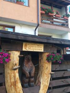 una estatua de un oso en una casa de troncos de árbol en Guest House Markovi, en Govedartsi