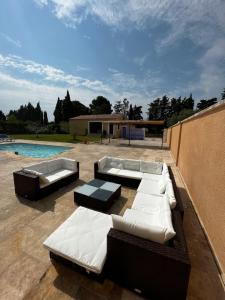 un patio con sofás blancos y una piscina en Magnifique maisonnette Dépendance avec Piscine en Châteaurenard