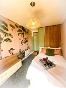 a bedroom with a large white bed and a chandelier at Travellers Tales - A Pod in the Cotswolds in Minster Lovell