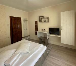 a bedroom with a white bed and a television at Pensiunea Aby in Sovata