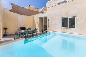 una piscina con mesa y sillas en una casa en Celestina Farmhouse, en Xagħra