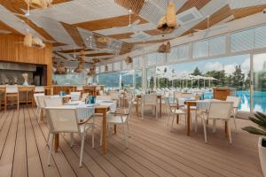 a restaurant with tables and chairs and a pool at Dukley Hotel & Resort in Budva