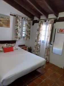 a bedroom with a white bed and two windows at Hotel El Jisu in Camaleño