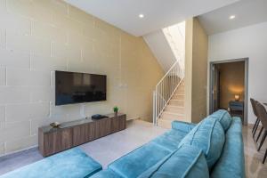 sala de estar con sofá azul y TV en Celestina Farmhouse en Xagħra