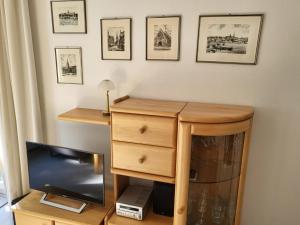 a room with a wooden dresser and a television at Kurpark Appartement in Glücksburg