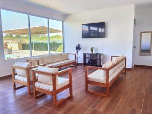 a living room with a couch and chairs and a television at Bungalow Sol del Sur in Paracas