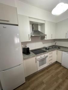 a kitchen with white cabinets and a white refrigerator at Piso Cernadas in Redondela
