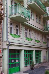 a building with green doors and a balcony at Apartment Lilianna in Karlovy Vary