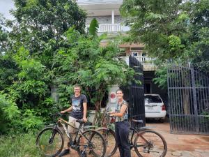 two people standing with their bikes in front of a gate at Realkhom Homestay in Siem Reap