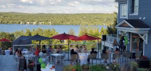 Un groupe de personnes assises à des tables avec des parapluies dans l'établissement Location Au Sommet du Lac Magog, à Magog