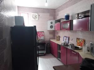 cocina con armarios rosados y nevera negra en Dany ka, en Naj‘ al Maḩaţţah