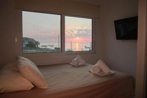 a bedroom with a bed with pillows and a large window at Stegna Sunny Beach- up floor in Archangelos