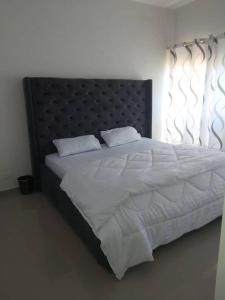 1 dormitorio con 1 cama grande con sábanas y almohadas blancas en Specious Old Zamtel flats en Lusaka