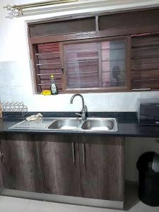 eine Küchentheke mit einem Waschbecken und einem Fenster in der Unterkunft Specious Old Zamtel flats in Lusaka