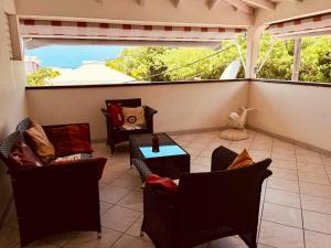 uma varanda com cadeiras, uma mesa e uma janela em Villa de 3 chambres avec vue sur la mer jardin clos et wifi a Le Gosier a 2 km de la plage em Le Gosier