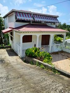 uma casa branca com um telhado vermelho numa estrada de terra em Villa de 3 chambres avec vue sur la mer jardin clos et wifi a Le Gosier a 2 km de la plage em Le Gosier