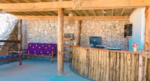 a room with a bar with a couch and a television at Jabali Bungalows Lodge in Paje