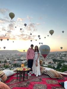 una pareja de pie en la cima de una montaña con globos de aire caliente en Doors Of Cappadocia Special Cave Hotel, en Göreme 212 fotos más