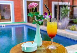 a drink and a vase with flowers on a table next to a pool at Angkor Rithy team in Siem Reap