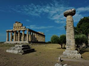 Eine Säule und ein Gebäude auf einem Feld in der Unterkunft Domus Clelia Paestum Antica Luxury rooms in Paestum