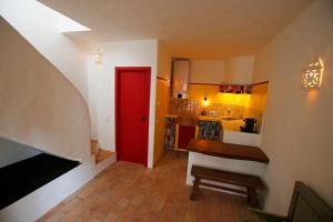 Habitación con puerta roja y cocina en Casa Amado, Aldeia da Pedralva, en Vila do Bispo