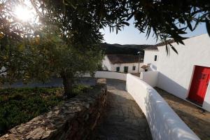 einen Steinweg vor einem weißen Gebäude mit einer roten Tür in der Unterkunft Casa Amado, Aldeia da Pedralva in Vila do Bispo