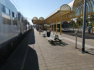 a train station with benches and a train at Vakantie Aan Zee in De Panne