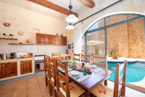 een keuken en eetkamer met een tafel en een zwembad bij Ta Indri Holiday Home in Żebbuġ