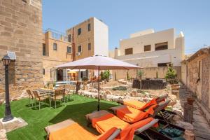 un patio con sillas, una sombrilla y una mesa en Ta Indri Holiday Home, en Żebbuġ
