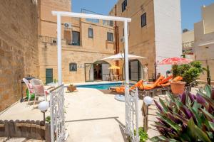 a pool with chairs and umbrellas next to a building at Ta Indri Holiday Home in Żebbuġ