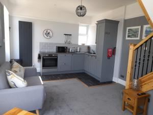 a living room with a couch and a kitchen at Eddystone Light Apartment in Mevagissey