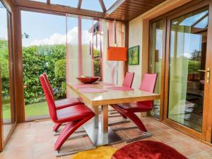 a dining room with red chairs and a wooden table at Marina House in Enniskillen