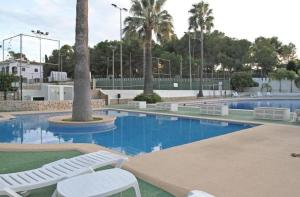 - une piscine avec 2 chaises blanches et des palmiers dans l'établissement Casita Pepe, à Jávea
