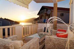 patio z wiklinowymi krzesłami i stołem na balkonie w obiekcie Apartment Levarda with private hydromassage pool w Okrugu Gornjim