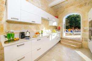 a kitchen with white cabinets and an arched doorway at Sulda Brill in Nadur