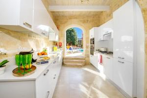 a kitchen with white cabinets and a large window at Sulda Brill in Nadur