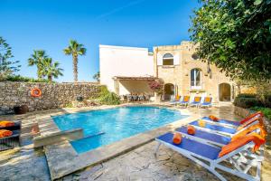a swimming pool with chairs and a house at Sulda Brill in Nadur