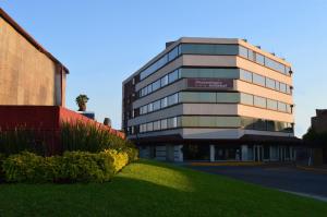 a building with a green lawn in front of it at Hotel Flamingo Kristal in Irapuato