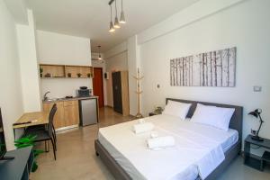 a bedroom with a large white bed and a kitchen at Facadoro Apartments in Athens