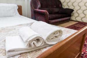 een bed met handdoeken en een stoel bij Самал с красивым видом из окна in Alma-Ata