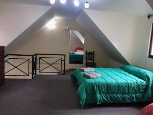 ein Schlafzimmer mit einem grünen Bett im Dachgeschoss in der Unterkunft Duplex Ushuaia Centro in Ushuaia