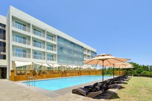 a hotel with a swimming pool with chairs and an umbrella at JEJU Shangrila Hotel& Resort in Jeju