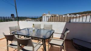 a glass table and chairs on a balcony at Townhouse half way between Javea and Moraira in Benitachell