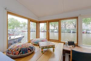 アムステルダムにあるThe Amsterdam Houseboat Family - de Jordaanの窓、テーブル、ベンチが備わるボートルーム