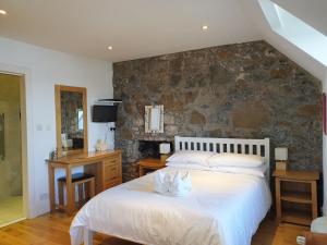 a bedroom with a bed and a stone wall at Harbour view in Tobermory