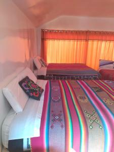 2 Betten in einem Zimmer mit bunten Decken in der Unterkunft Titicaca Kontiki Lodge Peru in Puno