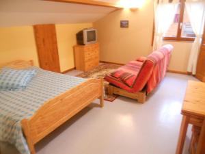 a bedroom with a bed and a chair and a tv at Auberge du Saut des Cuves in Xonrupt-Longemer
