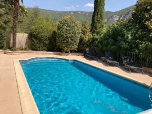 una piscina azul con sillas y montañas en el fondo en Studio 4 personnes, en Rivière-sur-Tarn