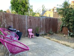 a patio with two pink chairs and a fence at A lovely guest room in West London in London